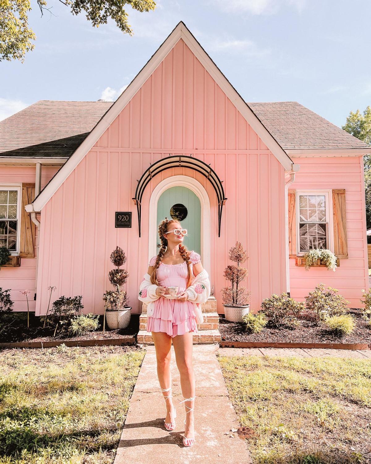 woman stands in front of pink house