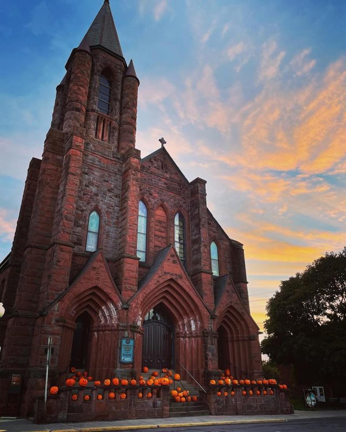 pumpkins line the steps of a large sandstone church