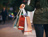 Picture of person holding shopping bags with downtown street view in background.