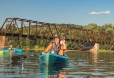 Alana From Susquehanna Greenway Partnership Kayaking on the river with a train bridge in the background