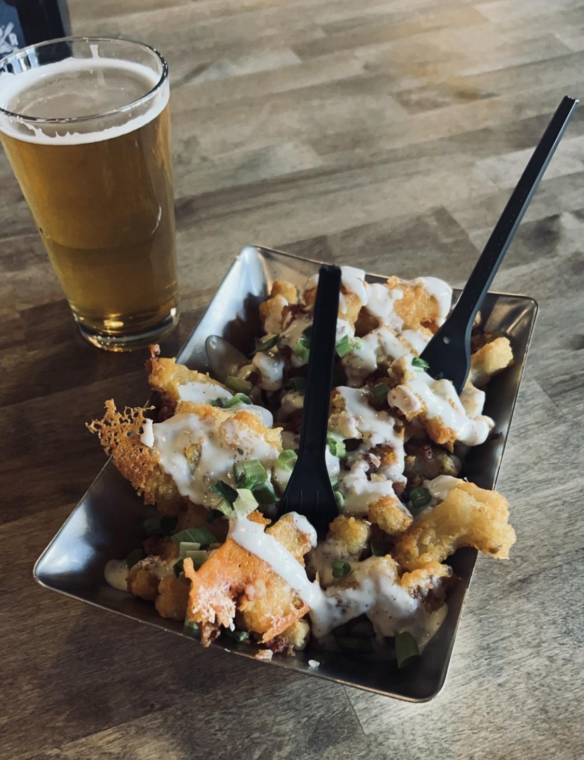 Food and drink from Hop River containing loaded tater tots and a beer