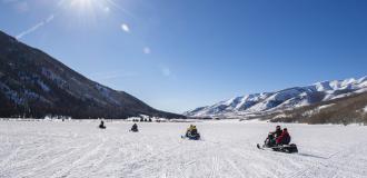 Group of snowmobiles in a wide-open field in Weber Canyon on sunny day.