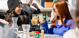 two girls cheers their drinks while outside