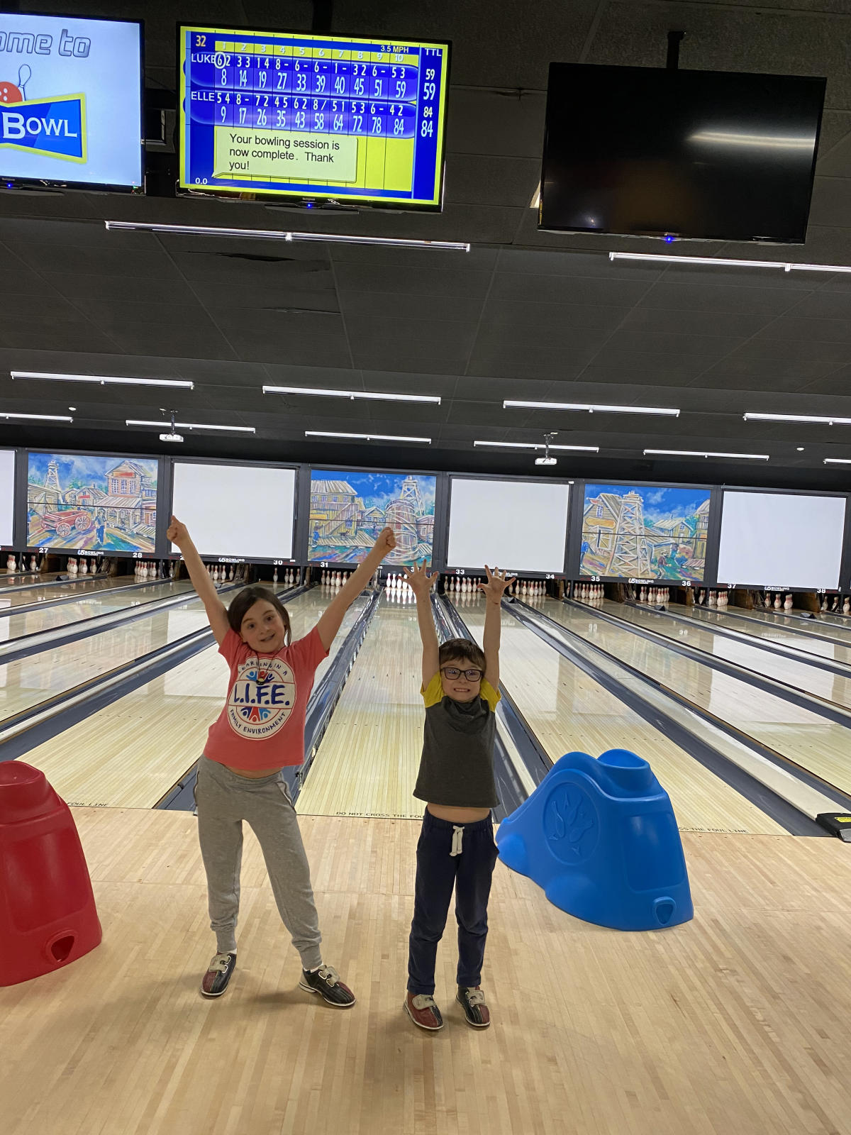 Two kids with their hands up in the air at Max Bowl