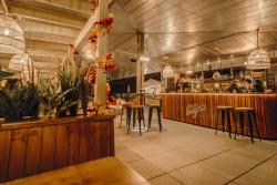 Meet Cambridge Douce Heights Restaurant roof terrace - a covered area with a white wood panelled ceiling & a timber fronted bar. Bar stools & banquette seating is in the background