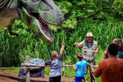 Man giving presentation about dinosaurs at Reptiland with people in the foreground watching.