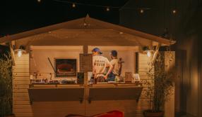 Meet Cambridge Douce Heights Oscar's pizza hut - a white wood cabin lit up on a dark night