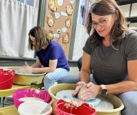 Picture of two people sitting at pottery wheels making pots at the YMCA Arts Center