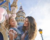 Mother and daughter holding a balloon in front of the castle at Magic Kingdom® Park