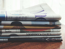 Stack of newspapers sitting on a wooden surface