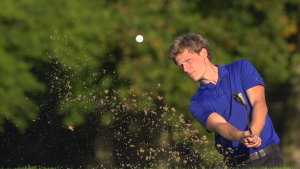 Man hitting a golf ball out of a sand trap in a Daytona Beach golf course