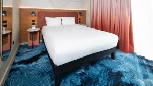 A hotel bedroom at ibis Styles in Burton upon Trent, Staffordshire, showing the bed, large window, and mirror on the wall