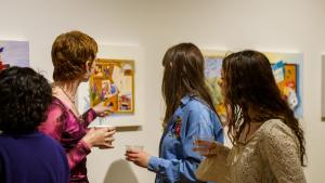 Four women view art in a gallery.