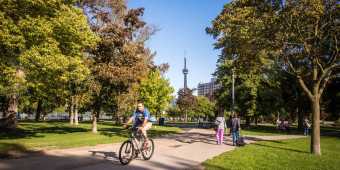 A person rides a bike through Trinity Bellwoods park