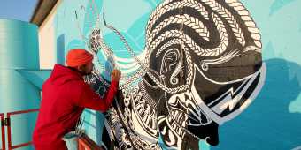 Adeyemi Adegbesan painting the Agents of Change mural (2021), part of the ALLSTYLE mural as seen at ArtworxTO Hub North: Downsview
