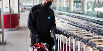 A staff member at Toronto Pearson disinfects baggage carts with a disinfecting fogging machine