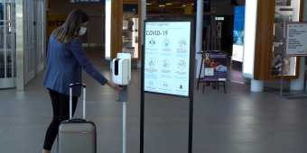 A person using the hand sanitizer station at Billy Bishop Airport