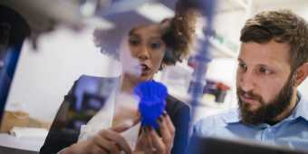 Man and woman inspect blue object printed with 3D printer
