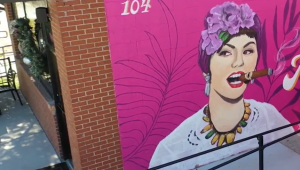 Hot pink mural of young woman smoking a cigar at Guava Tree Cuban Cafe & Cantina