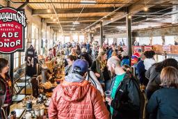 A bustling crowd shopping in a large market area.
