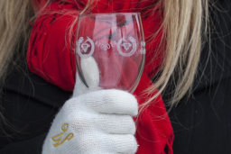 A woman wearing a red scarf and white gloves holding a wine glass.