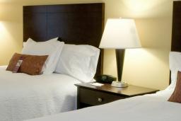 Man reading the newspaper in his Hotel Room with two beds and two lamps