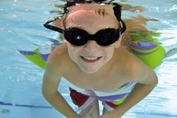 Boy in swimming pool with goggles and a floaty on family getaway in Providence