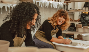 two friends laughing in a pottery class