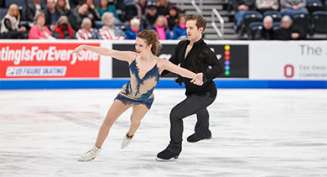 A male and female ice skate together during a competition