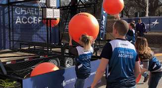People shoot large basketballs through hoops at a fan fest event