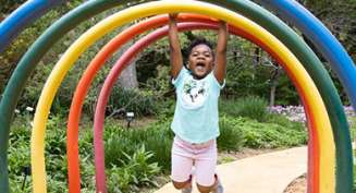 A young girl hands from a rainbow arch at the Children's Garden inside Botanica Wichita.