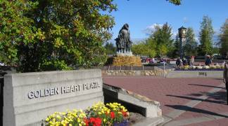 View of Golden Heart Plaza, featuring a statue, clock tower, flowers and trees.