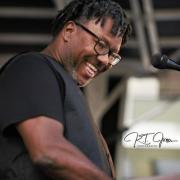 Cliff Starkey smiles showing his teeth whole playing the keyboard and singing.