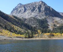 angler in a float tube on lundy lake with the fall colors and mountains as backdrop