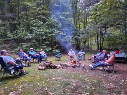 Picture of people sitting around a campfire in the woods at Gray Squirrel Campground