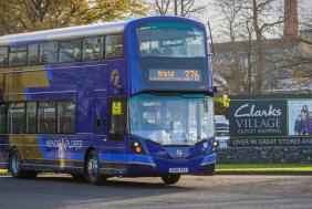 A purple and beige-coloured Mendip Explorer 376 bus parked at Clarks Village in Street, Somerset - First Bus