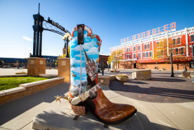 A vibrant boot sculpture in downtown Cheyenne under the Cheyenne Depot arch with historic buildings in the background, capturing top historic things to do.