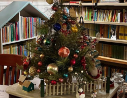 Cottage on Pine Holiday Display - A tree with vintage ornaments and vintage books on shelves in the background.