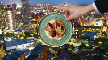 A waiter holds up a plate of food with a cityscape in the background