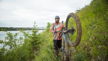A mountain biker shows the mud on his tires from biking the trails.