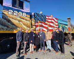 Picture of the North Shore Railroad America 250 PA Train Unveiling ceremony. Train in the background with a row of elected officials and mural artist in foreground.