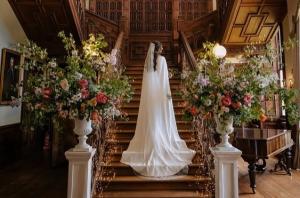 A bride in her wedding dress climbs the beautiful staircase at Sandon Hall, Staffordshire