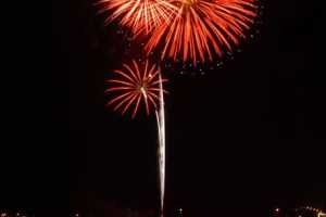 three red fireworks shooting off over a body of water