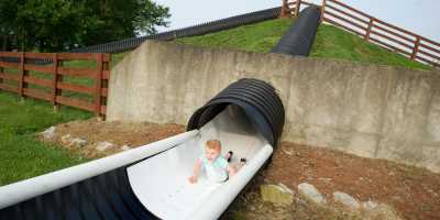 Young boy sliding down head first on a hill slide at Huber's Orchard, Winery & Vineyards