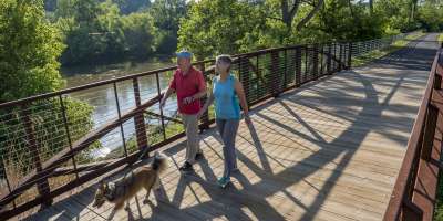 Couple walking dog along French Broad River Greenway