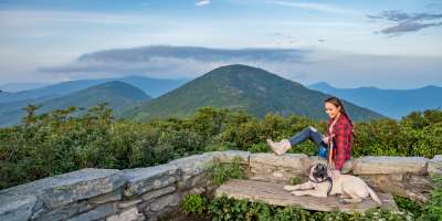 A young woman sits with her dog at Craggy Gardens Pinnacle near Asheville, NC