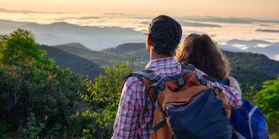 Backpackers happy young couple hiking with sticks Stock Photo by