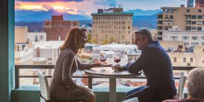 Couple enjoys glasses of wine atop the AC Hotel rooftop balcony.