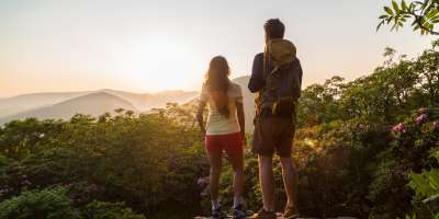 A couple watches the sun setting behind the western mountains from atop Craggy Gardens.