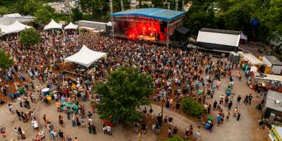 Aerial photo of a crowd surrounded outside near a stage at Salvage Station